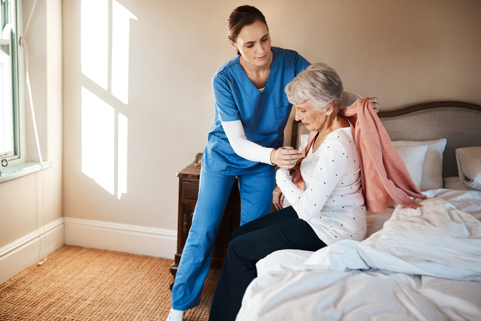 Nurse, old woman and dressing in bedroom, support and trust with rehabilitation, recovery and healing. House, medical and professional with patient, caregiver and health with assistance