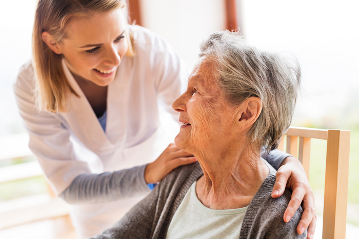 A home health care nurse talking to an elderly woman.